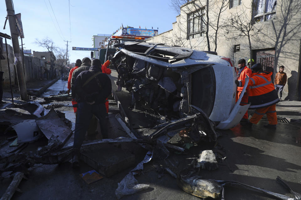 Afghan security personnel and municipality workers remove a damaged vehicle after a roadside bomb attack in Kabul, Afghanistan, Tuesday, Dec. 22, 2020. A roadside bomb tore through a vehicle in the Afghan capital of Kabul Tuesday, killing multiple people, police said. (AP Photo/Rahmat Gul)