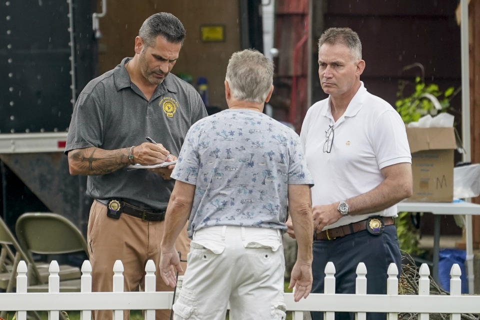 FILE - Etienne DeVilliers, center, a next-door neighbor speaks to authorities working outside as they search the home of Gilgo Beach serial killer suspect Rex Heuermann, Wednesday, July 19, 2023, in New York. As new details emerge about how police finally caught the alleged killer, they've also raised questions about whether investigators adequately pursued a key lead that may have helped solve the case sooner. (AP Photo/John Minchillo, File)