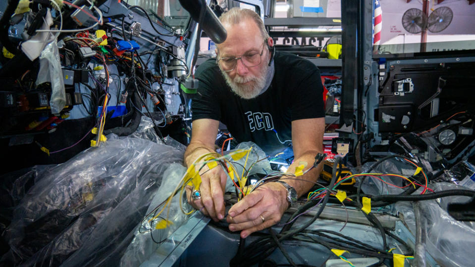 A craftsman at E.C.D. Automotive Design works on the intricate array of wiring inside Project Britton, an all-electric Defender 110 restomod.
