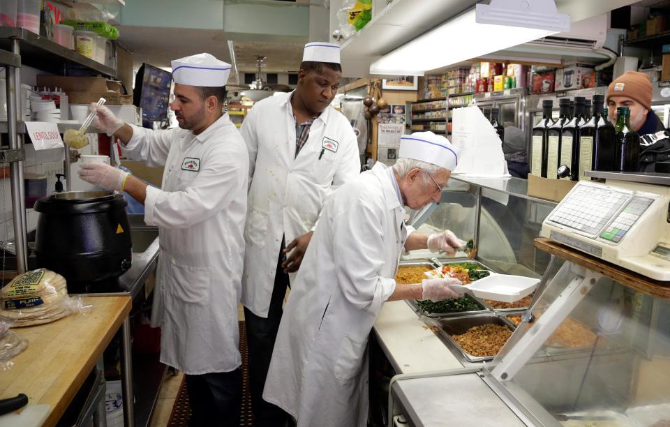 In this Nov. 21, 2013 photo, Amine Dekkar, left, and chef Arpiar Afarian, right, serve diners in the tiny upstairs deli at Kalustyan's Indian/Middle Eastern spice and specialty food shop in New York. They dole out hummus, falafel, moussaka, stuffed grape leaves, 16 types of olives, and more varieties of feta cheese than you’ll know what to do with. The not-so-little gem of a shop nestled into a row of like-minded stores on Lexington Avenue is known to New Yorker foodies, but off the map for most tourists. (AP Photo/Richard Drew)