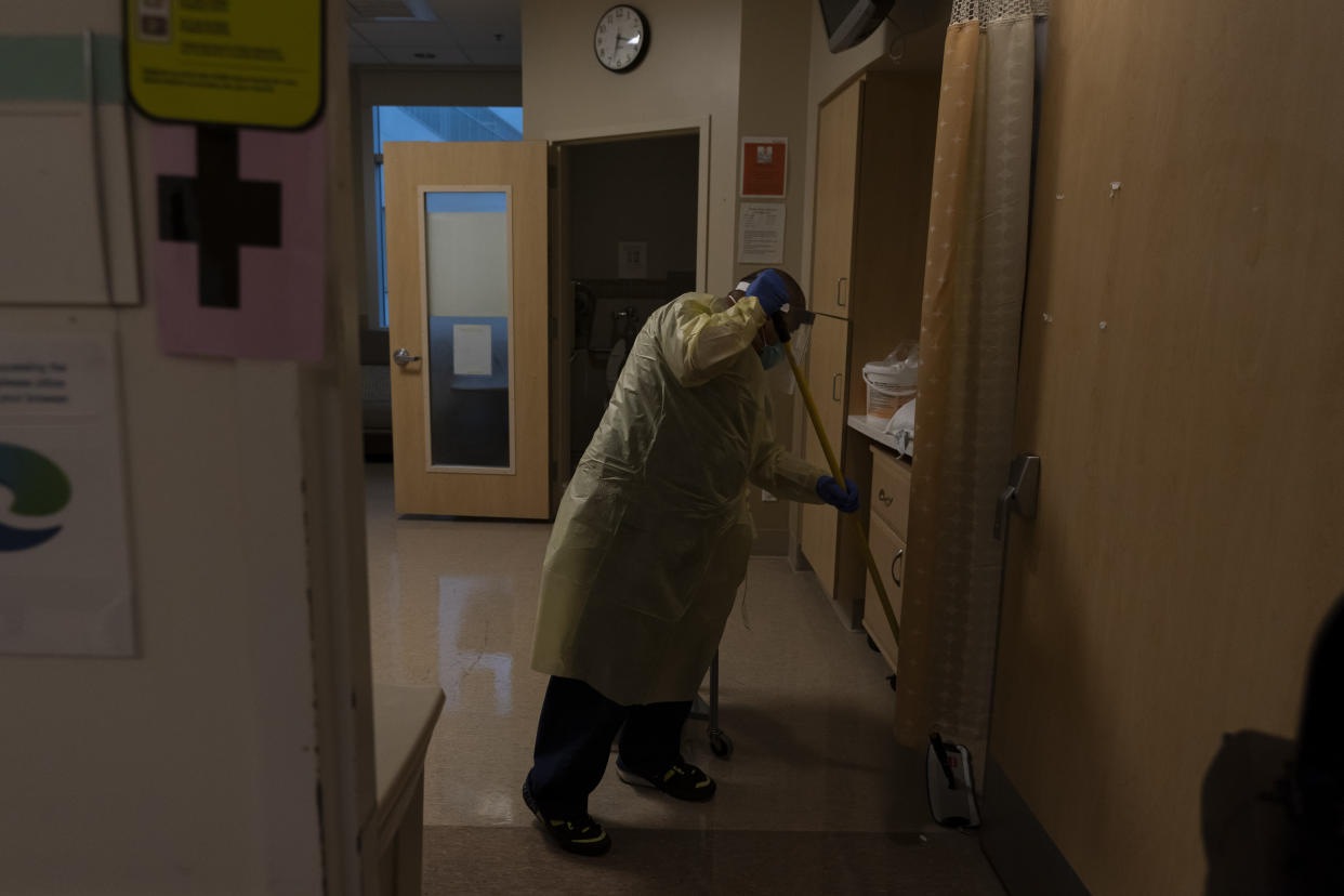 Environmental technician Gerardo Velazquez cleans a room after a COVID-19 patient was transferred to an intensive care unit at Providence Holy Cross Medical Center in Los Angeles, Monday, Dec. 13, 2021. At Los Angeles' Providence Holy Cross Medical Center, just 17 coronavirus patients were being treated there Friday, a small fraction of the hospital's worst stretch. Nurse manager Edgar Ramirez said his co-workers are weary but better prepared if a wave hits. (AP Photo/Jae C. Hong)