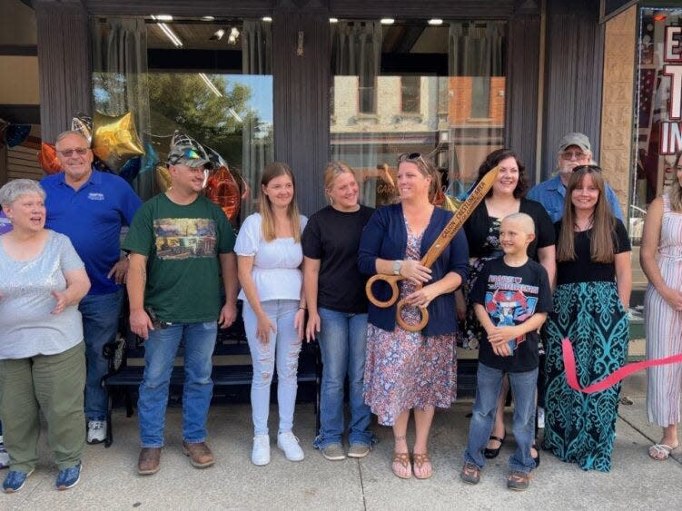 Carrie Cottrell holds the scissors provided by the Galion-Crestline Area Chamber of Commerce after cutting the ribbon during the recent opening celebration of her new business, Carrie's Venue, located at 129 Harding Way East in Galion.