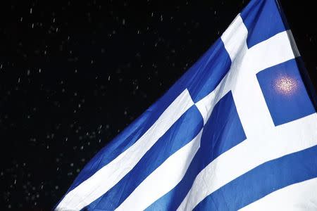 A Greek national flag waves under rainfall during a rally of the Greek Communist party in Athens February 27, 2015. REUTERS/Alkis Konstantinidis