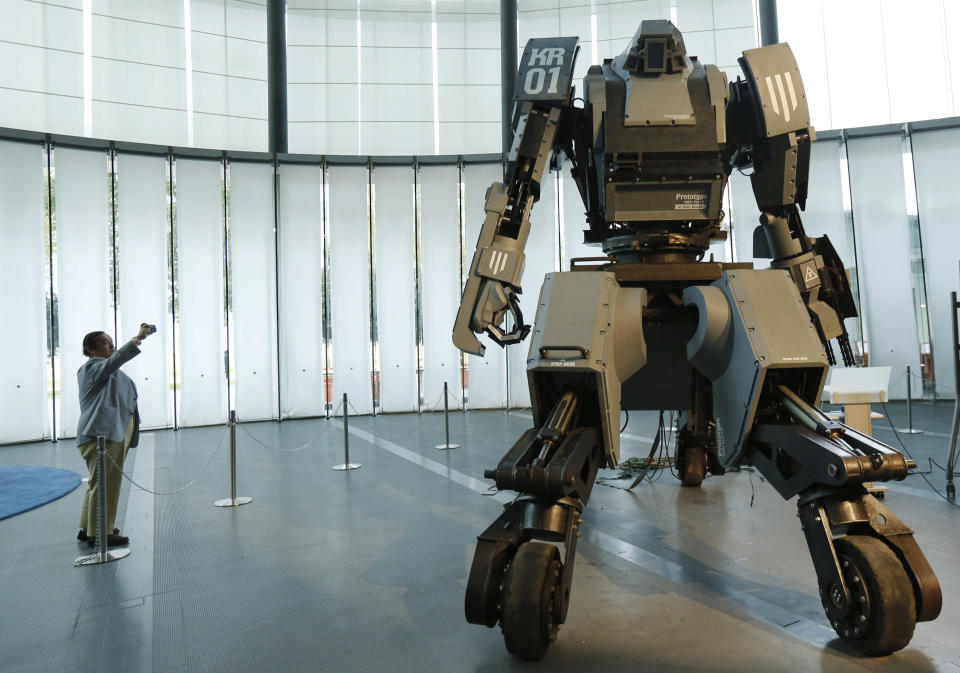 A man takes a picture of a giant "Kuratas" robot at an exhibition in Tokyo