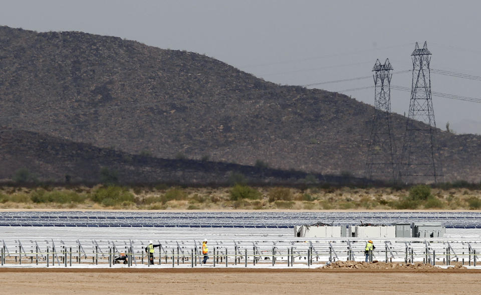 FILE - Workers continue to build rows of solar panels at a Mesquite Solar 1 facility under construction in Arlington, Ariz., Sept. 30, 2011. One of President Joe Biden's signature laws aimed to invigorate renewable energy manufacturing in the U.S. It will also helped a solar panel company reap billions of dollars. Arizona-based First Solar is one of the biggest early winners from the Democrats' Inflation Reduction Act, offering a textbook case of how the inside influence game works in Washington.(AP Photo/Ross D. Franklin, File)