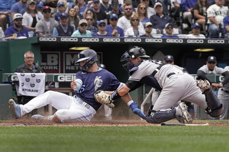 Kansas City Royals' Whit Merrifield, left, is tagged out by New York Yankees catcher Kyle Higashioka as he tried to score on a fielder's choice hit by Salvador Perez during the third inning of a baseball game Sunday, May 1, 2022, in Kansas City, Mo. (AP Photo/Charlie Riedel)