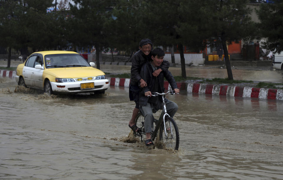 Afghan boys rides a bicycle through floodwaters as heavy rain falls in Kabul, Afghanistan, Tuesday, April 16, 2019. Afghan officials say at least five more people have been killed and 17 are missing as a new wave of heavy rains and flooding swept across the country's western Herat province. (AP Photo/Rahmat Gul)