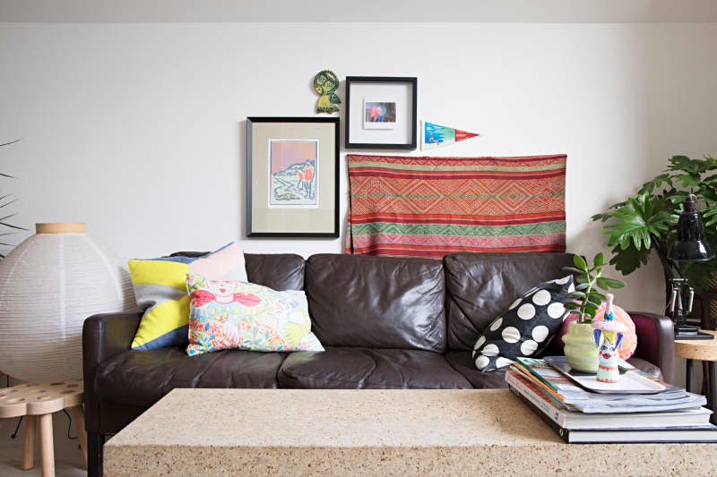 brown leather couch with colorful throw pillows and terrazzo coffee table