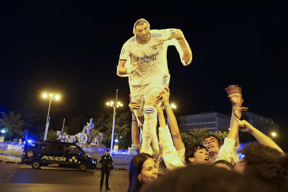 Real Madrid supporters celebrate with a figure of Real Madrid's Karim Benzema at the end of the Champions League soccer final in Cibeles square in downtown Madrid, Spain, Sunday, May 29, 2022. Real Madrid beat Liverpool 1-0 in the Champions League final in Paris. (AP Photo/Andrea Comas)