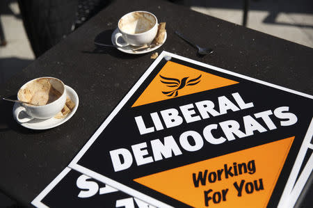 Liberal Democrat signs lie next to empty coffee cups on a table at a pub in Surbiton, west of London, April 6, 2015. REUTERS/Neil Hall