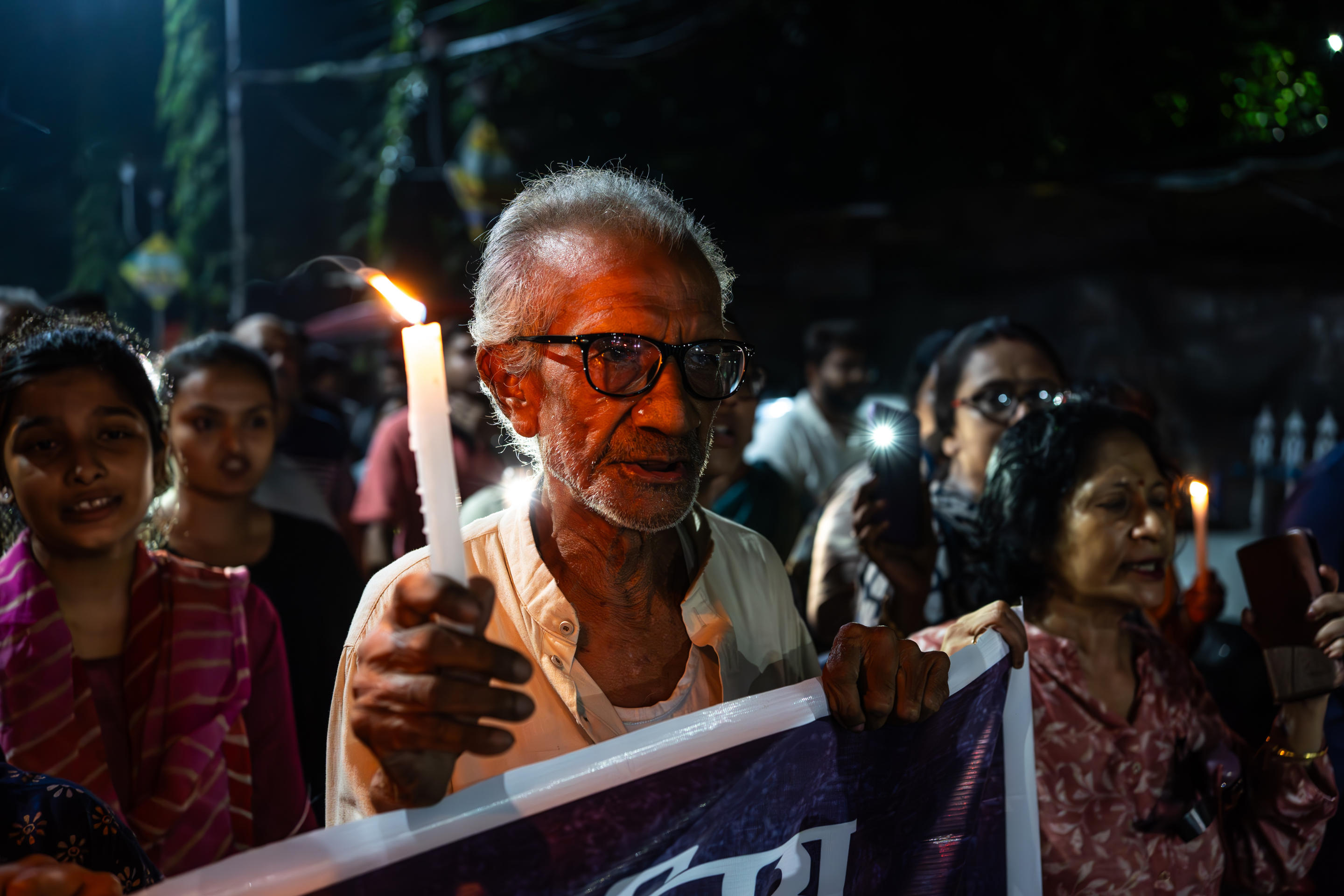 A man holds a candle as a sign of respect and demand for justice for the murdered rape victim. 