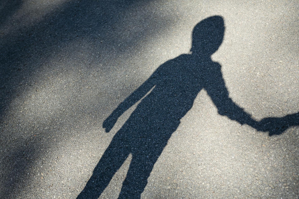 Shadow of a person on pavement, holding hands with a child's shadow