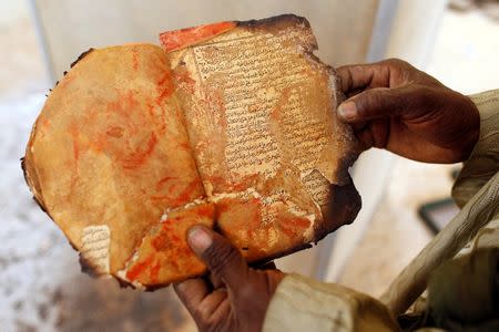 A museum guard displays a burnt ancient manuscript at the Ahmed Baba Institute, or Ahmed Baba Centre for Documentation and Research, in Timbuktu January 31, 2013. REUTERS/Benoit Tessier/Files
