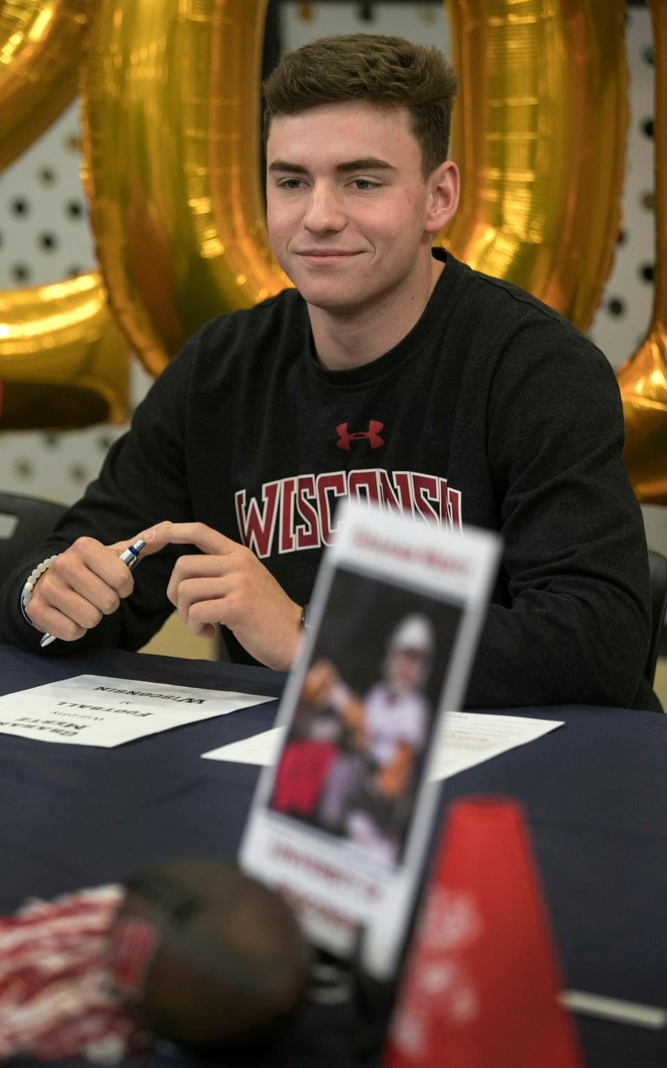 In this Dec. 19, 2019, photo, Graham Mertz acknowledges his intent to play at Wisconsin during a signing ceremony at Blue Valley North High School in Overland Park, Kansas.