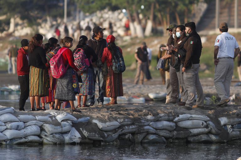 Agentes migratorios mexicanos piden identificación a migrantes en el río Suchiate, en la frontera con Guatemala