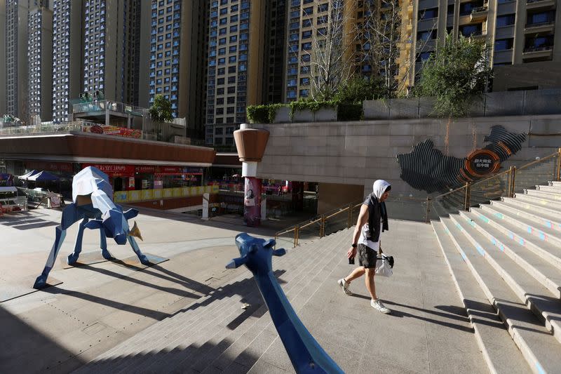 A man walks past residential buildings next to the Evergrande City Plaza in Beijing