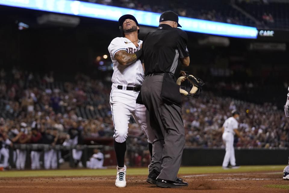 Arizona Diamondbacks' David Peralta, left, collides with umpire Jeff Nelson, right, after scoring a run against the St. Louis Cardinals during the third inning of a baseball game Friday, May 28, 2021, in Phoenix. (AP Photo/Ross D. Franklin)