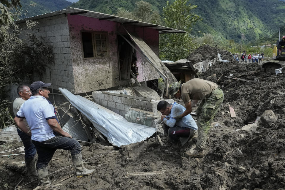 A resident, kneeling, reacts after landslides damaged his house in El Placer, Ecuador, Monday, June 17, 2024. (AP Photo/Dolores Ochoa)