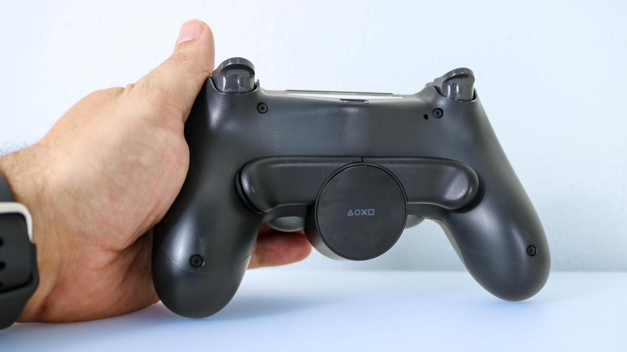  The DualShock 4 Back Button Attachment attached to a controller on a desk. 