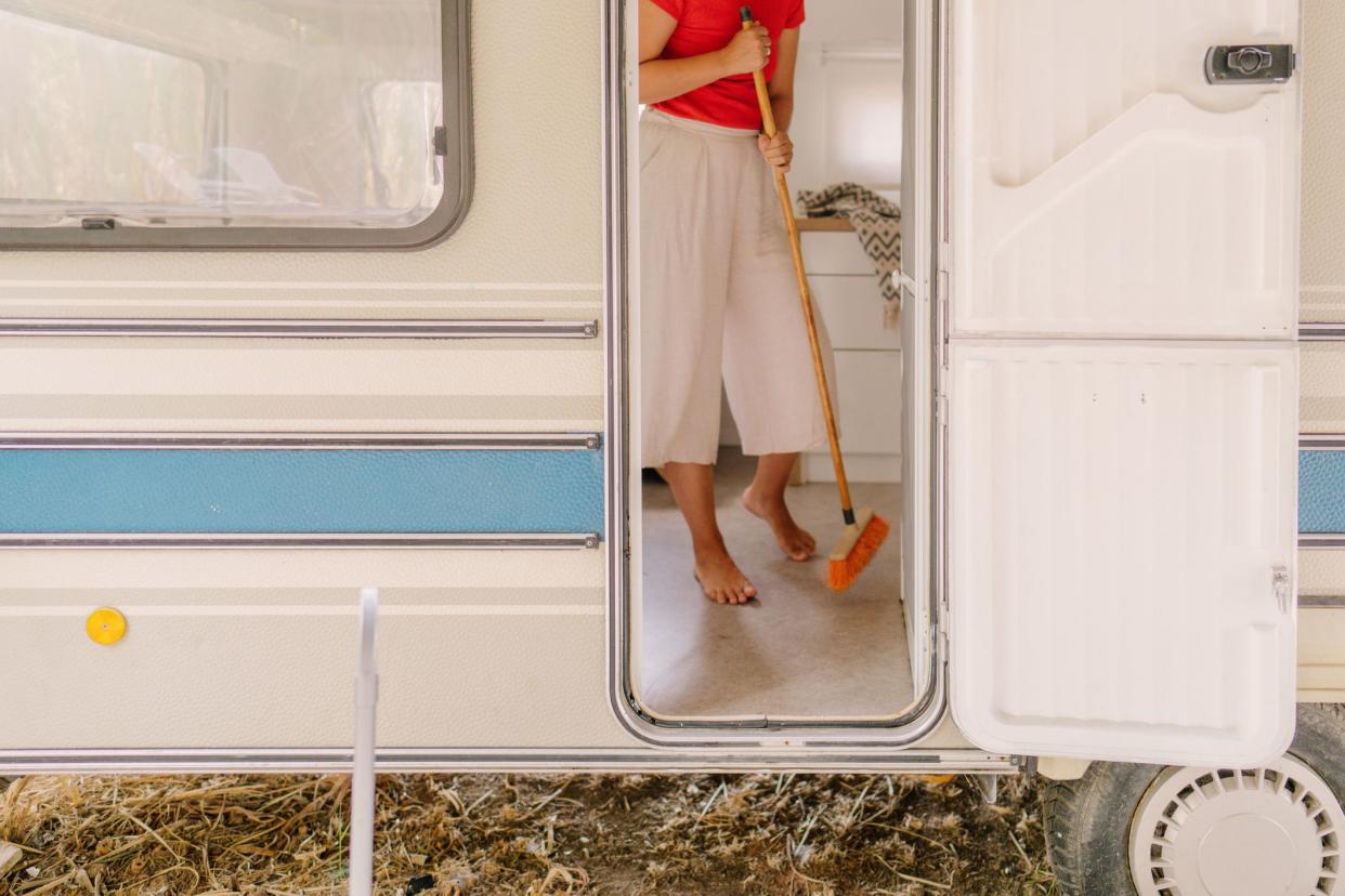 Photo of a young woman cleaning and sweeping the inside of her RV.