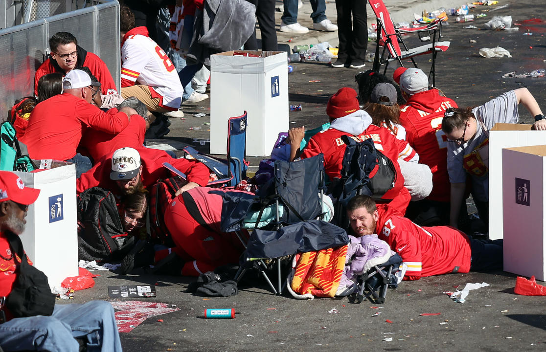 People take cover and huddle on the ground during a shooting.