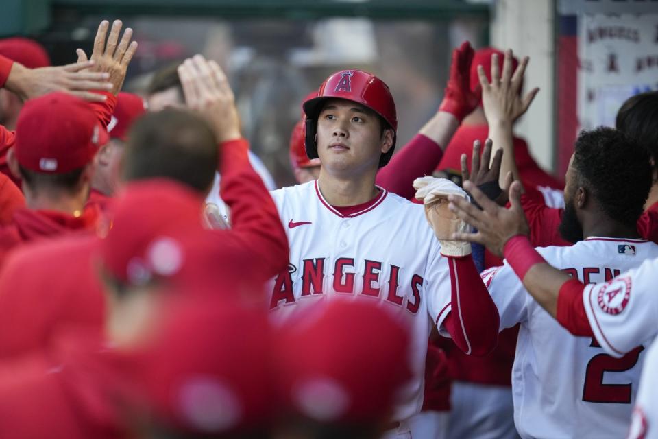 Angels' Shohei Ohtani high-fives fellow players.