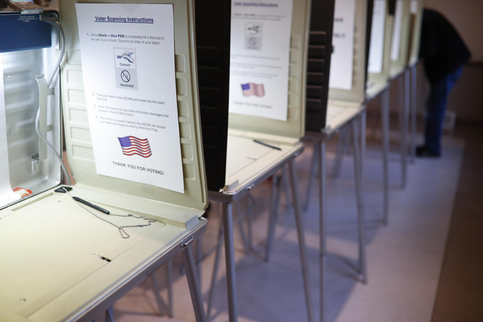 FILE- In this Nov. 8, 2016, file photo a lone voter fills out a ballot alongside a row of empty booths at a polling station in the Terrace Park Community Building on Election Day in Cincinnati. Microsoft announced Monday, May 6, 2019, an ambitious effort to make voting secure, verifiable and reliably auditable with open-source software that top U.S elections vendors say they will explore incorporating into new and existing voting equipment. (AP Photo/John Minchillo, File)