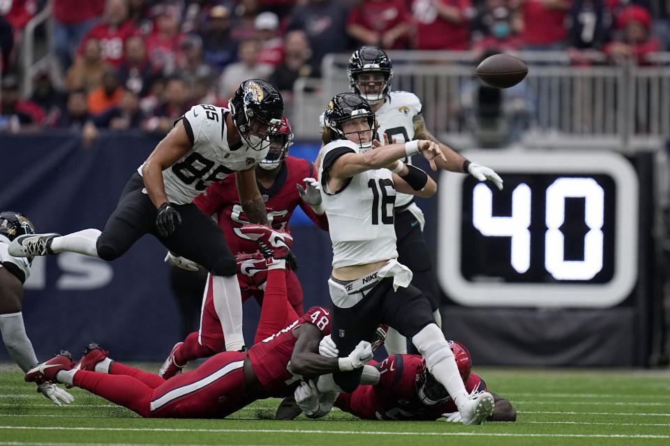 Jacksonville Jaguars quarterback Trevor Lawrence (16) throws an incomplete pass as he tackled by Houston Texans linebacker Christian Harris (48) in the first half of an NFL football game in Houston, Sunday, Nov. 26, 2023. (AP Photo/Eric Gay)