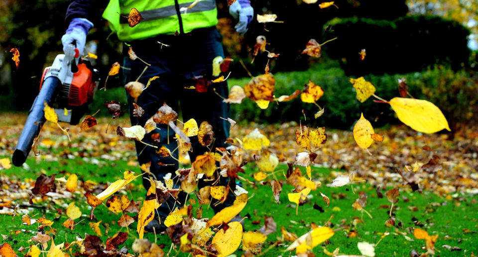 A worker clears leaves with a leaf blower in Swadlincote, south Derbyshire during autumn.