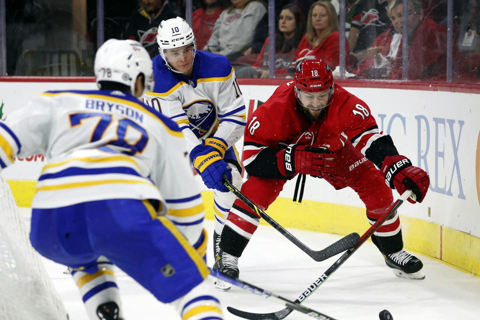 Carolina Hurricanes' Derek Stepan (18) reaches for the puck between Buffalo Sabres' Jacob Bryson (78) and Henri Jokiharju (10) during the second period of an NHL hockey game in Raleigh, N.C., Saturday, Dec. 4, 2021. (AP Photo/Karl B DeBlaker)