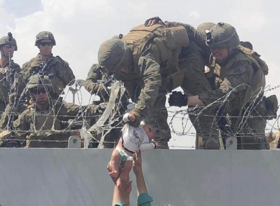 This image made available to AFP on August 20, 2021 by Human Rights Activist Omar Haidari, shows a U.S. Marine grabbing an infant over a fence of barbed wire during an evacuation at Hamid Karzai International Airport in Kabul on August 19, 2021. / Credit: Courtesy of Omar Haidiri/AFP/Getty