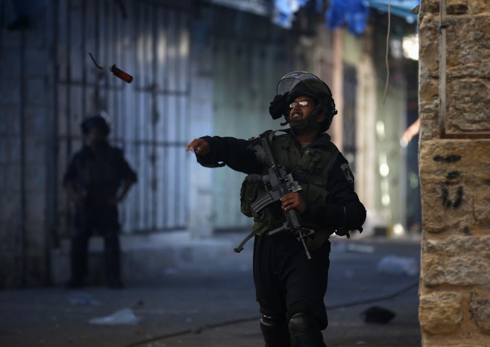 An Israeli border police throws a stun grenade at Palestinian stone throwers during clashes in the West Bank city of Hebron