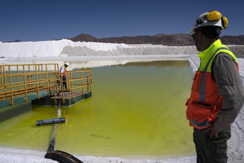 Staff at the Albemarle lithium mine walk along a pool of brine highly concentrated in lithium at Chile's Atacama Desert, Monday, April 17, 2023. (AP Photo/Rodrigo Abd)