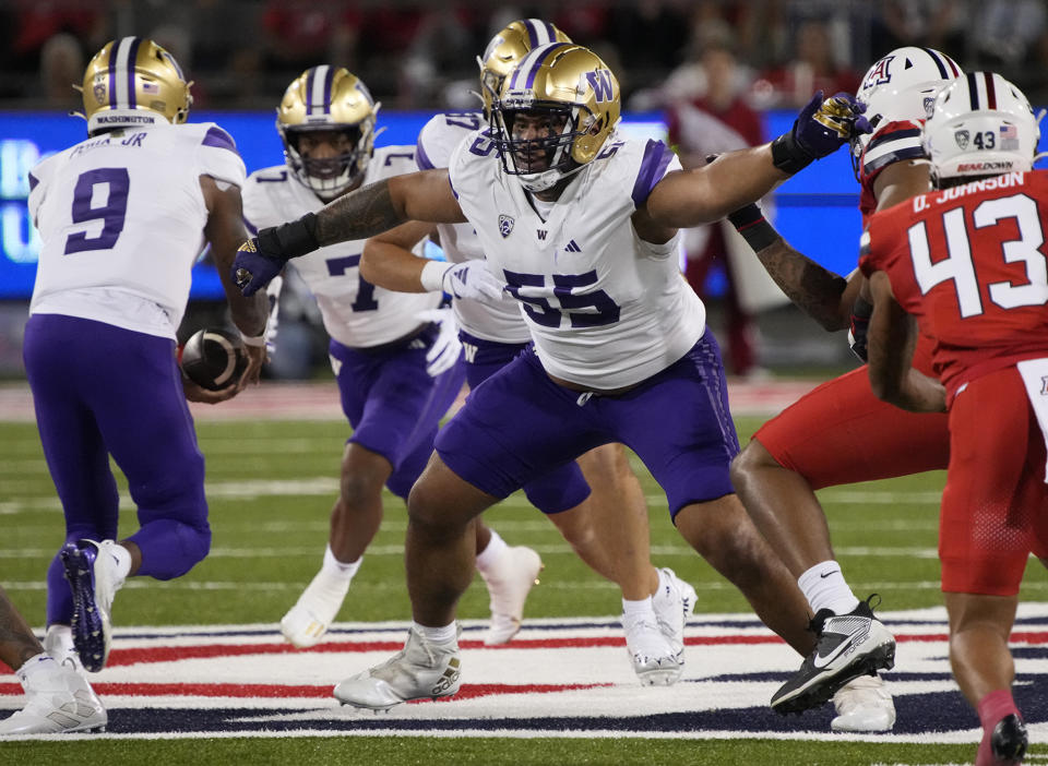 FILE - Washington offensive lineman Troy Fautanu (55) blocks for running back Dillon Johnson (7) who takes a handoff from quarterback Michael Penix Jr. (9) during the team's NCAA college football game against Arizona on Sept. 30, 2023, in Tucson, Ariz. The Pittsburgh Steelers selected Fautanu with the 20th overall pick in the first round of Thursday's NFL draft, giving them a potential bookend to last year's top pick Broderick Jones. (AP Photo/Rick Scuteri, File)