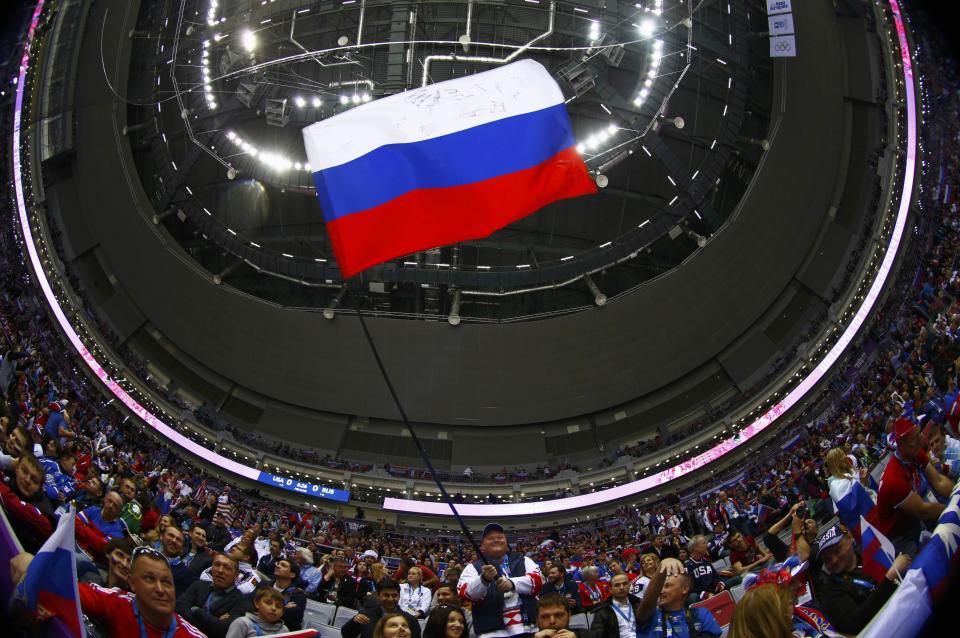 A fan waves a Russian flag before the men's preliminary round hockey game between Russia and USA at the Sochi 2014 Winter Olympic Games February 15, 2014. Picture taken with a fisheye lens. REUTERS/Mark Blinch (RUSSIA - Tags: OLYMPICS SPORT ICE HOCKEY TPX IMAGES OF THE DAY)