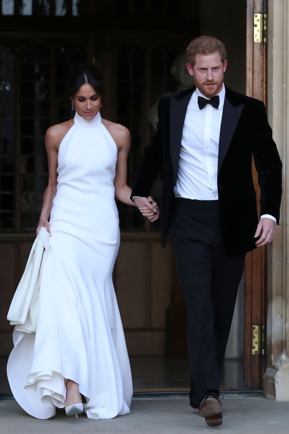 <p>For the evening's wedding reception, Markle changed into a high-neck fishtail gown by Brit designer Stella McCartney.</p><p>The bride teamed her silk-crepe halterneck dress with <a href="http://www.cartier.co.uk/en-gb/collections/jewelry/collections/reflection-de-cartier/earrings/h8000215-age-d_or-de-cartier-earrings.html" rel="nofollow noopener" target="_blank" data-ylk="slk:Reflection De Cartier;elm:context_link;itc:0;sec:content-canvas" class="link ">Reflection De Cartier</a> diamond and white gold earrings, white court shoes and a chic chignon. </p>