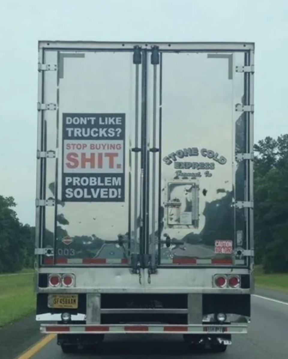 The back of a truck has a sign that reads, "Don't like trucks? Stop buying shit. Problem solved!" The truck's company name is Stone Cold Express