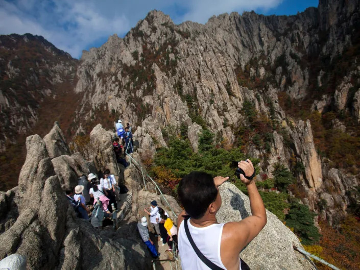 In this Saturday Oct. 8, 2011 photo, a North Korean man records video of the scenery as he and fellow hikers climb to a peak of Mount Kumgang, North Korea.