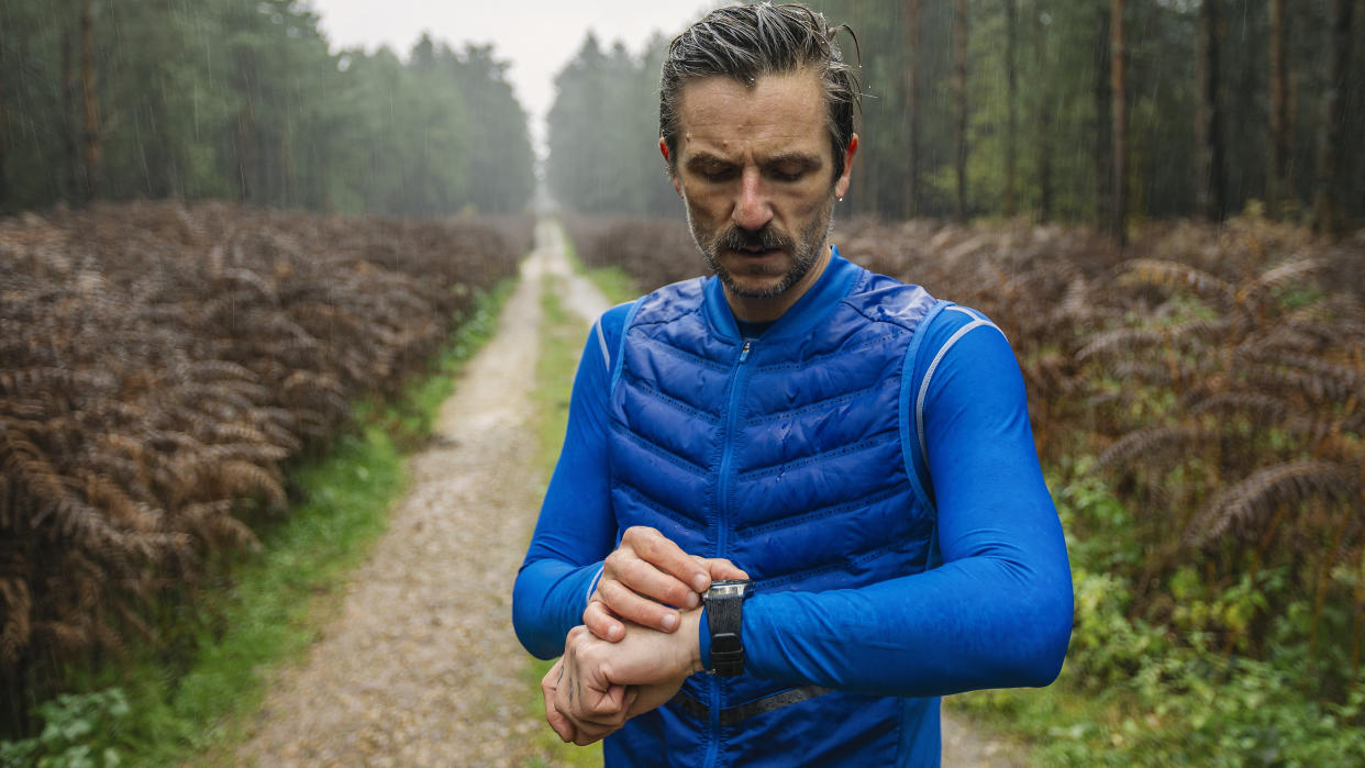  Man checking running watch in the rain. 