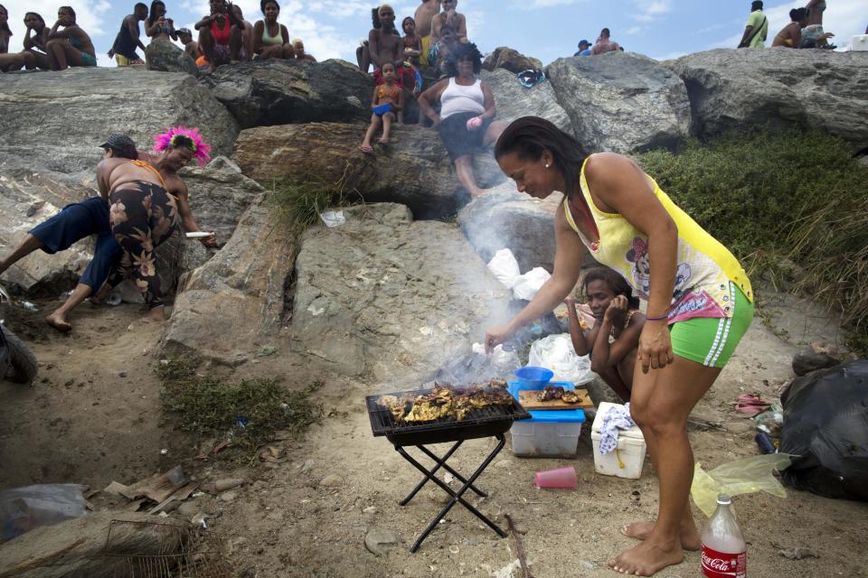 In this March 3, 2014 photo, a woman cooks a barbecue on the beach in La Guaira, Venezuela. There is plenty of discontent among the lower classes but the students have failed to capitalize on it. The students have not clearly articulated an agenda, says Luis Vicente Leon, director of the Datanalisis polling firm, and are divided among moderates and radicals just like the main opposition parties. (AP Photo/Rodrigo Abd)