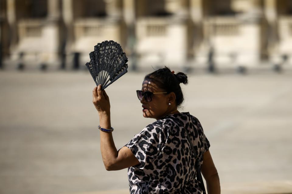 FILE - A woman uses a fan in the courtyard of the Louvre museum, Sept. 7, 2023, in Paris. Europe is facing growing climate risks and is unprepared for them, the European Environment Agency said in its first-ever risk assessment for the bloc Monday, March 11, 2024. (AP Photo/Thomas Padilla, File)