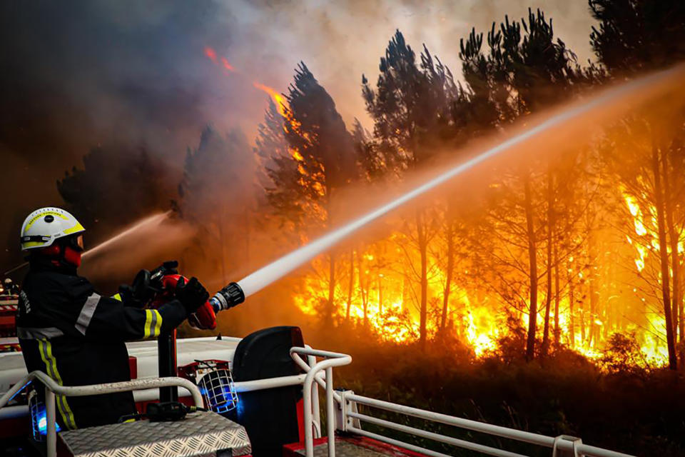 This photo provided Friday July 15, 2022 by the fire brigade of the Gironde region (SDIS 33) shows firefighters using hose to fight a wildfire near Landiras, southwestern France, Thursday, July 14, 2022. Several hundred firefighters struggled Friday to contain two wildfires in the Bordeaux region of southwest France that have forced the evacuation of 10,000 people and ravaged more than 7,000 hectares of land. High temperatures and strong winds have complicated firefighting efforts in the region, one of several around Europe scorched by wildfires this season. (SDIS 33 via AP)