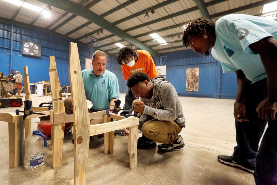 Jeff Maines, left, construction instructor with Project YouthBuild Americorps at the time, assists Johnathan Davis, 20, next to Maines, Ronaldo Rawls, 18, center, and Greg Sercey, 23, as they use scrapped wood pallets to build furniture with Project YouthBuild Americorps to be sold at a Farmer Markets in 2013.