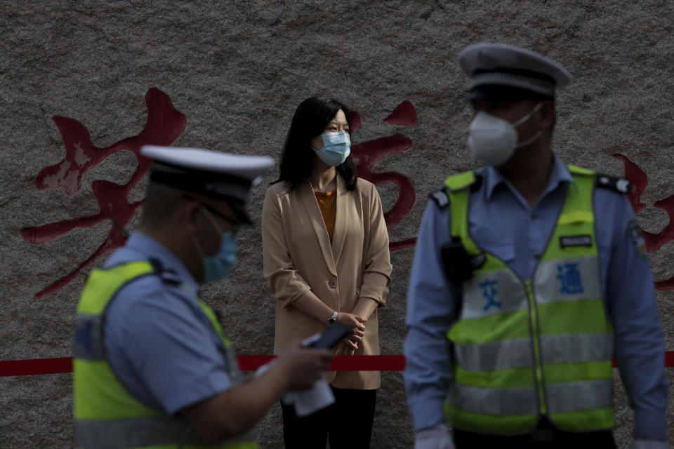 A teacher wearing a protective face mask to help curb the spread of the new coronavirus waits for arrival of the students outside a primary school in Beijing, Monday, June 1, 2020. With declining virus case numbers, students have gradually returning to their classes in the capital city. (AP Photo/Andy Wong)