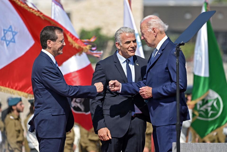 President Joe Biden is welcomed by Israel's President Isaac Herzog, left, and caretaker Prime Minister Yair Lapid upon his arrival at Ben Gurion Airport in Lod near Tel Aviv on Wednesday.