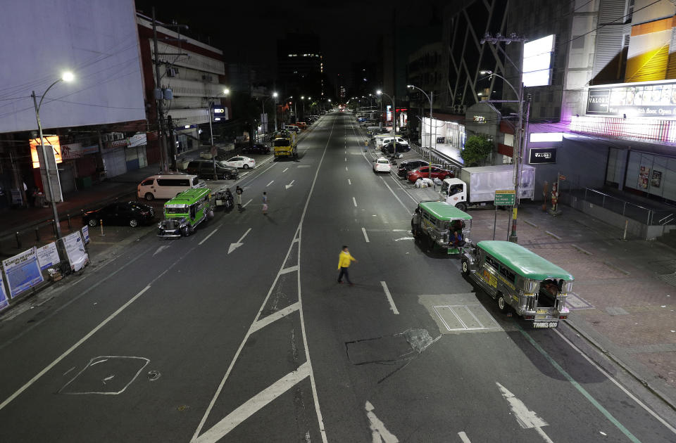 A man crosses an almost empty street shortly past midnight at Quezon city in Manila, Philippines early Tuesday, March 17, 2020 as the government implements an "enhanced community quarantine" that requires millions of people to stay mostly at home in an attempt to contain the new coronavirus. For most people, the new coronavirus causes only mild or moderate symptoms. For some, it can cause more severe illness, especially in older adults and people with existing health problems. (AP Photo/Aaron Favila)