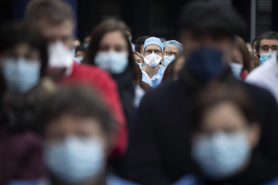 Medical staff observe a minute of silence while protesting a lack of resources outside the Strasbourg University Hospital, eastern France, Friday Jan. 14, 2022. The omicron variant is exposing weaknesses at the heart of Europe's public health system. In France and Britain, a sharp rise in coronavirus hospitalizations coupled with staff falling sick has led to a shortage of beds. (AP Photo/Jean-Francois Badias)