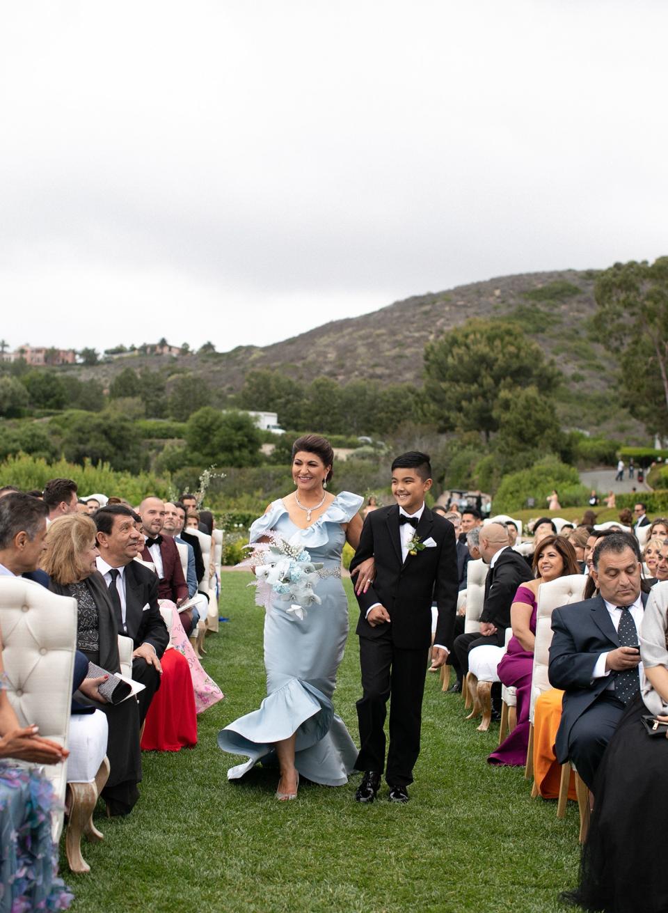 My stunning mother in a custom Nina Tiari gown, escorted down the aisle by my oldest nephew and her grandson, Kaveh Bakhtiari.