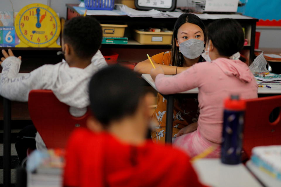 Teacher Mary Yi, wearing a mask, works with a fourth grade student in a classroom in Chelsea, Massachusetts.