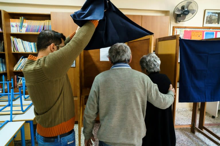 A Greek Cypriot voter in Nicosia is escorted to the voting booth on February 4, 2018 during the second round of the Cyprus presidential elections